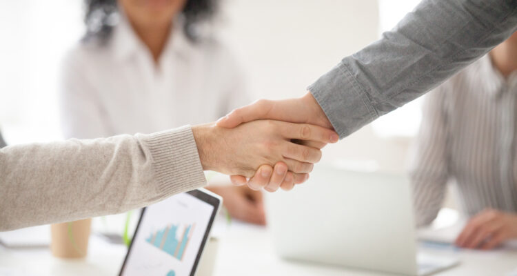 Business partners handshaking at group meeting making project in